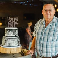 Guest of honour beside a tiered cake at an 80th birthday celebration